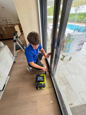 Technician carefully lifting sliding glass door off track using proper technique