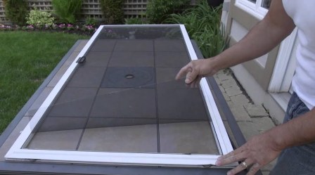 Technician removing old damaged screen mesh and rubber spline from aluminum frame