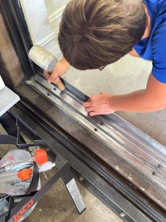 Technician using specialized straightening tools to repair bent aluminum sliding door track